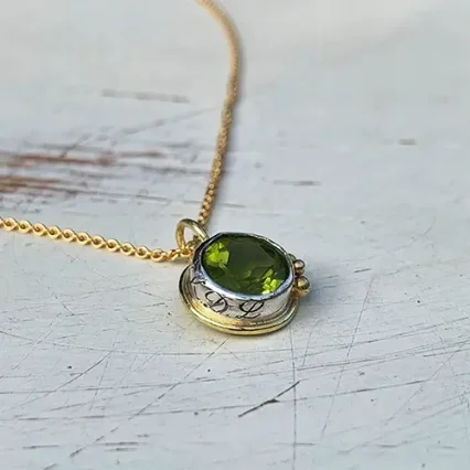 Een gravure siert de rand van dit gedenksieraad met geboortesteen